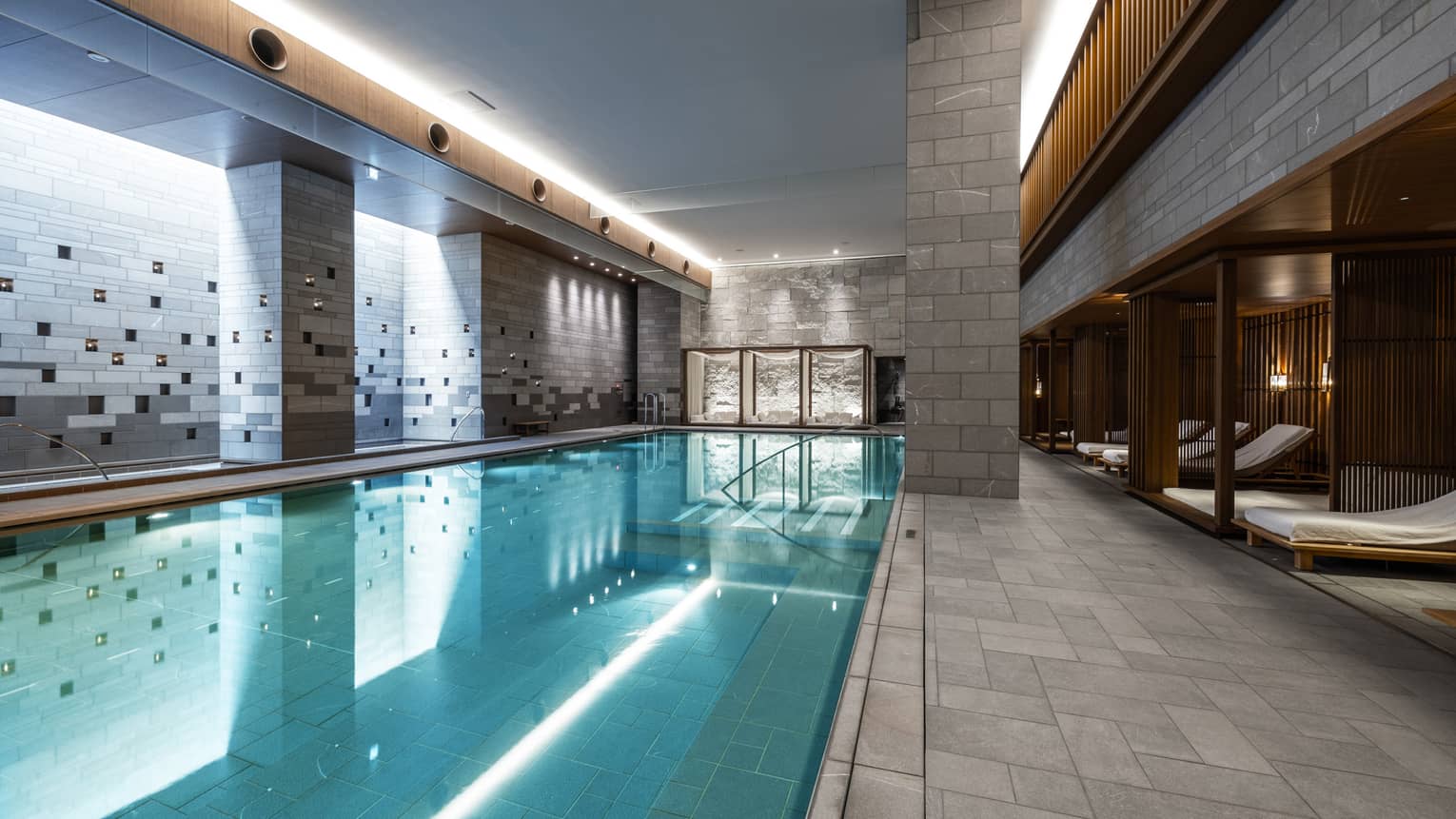 Indoor spa pool with chaise longues and grey columns