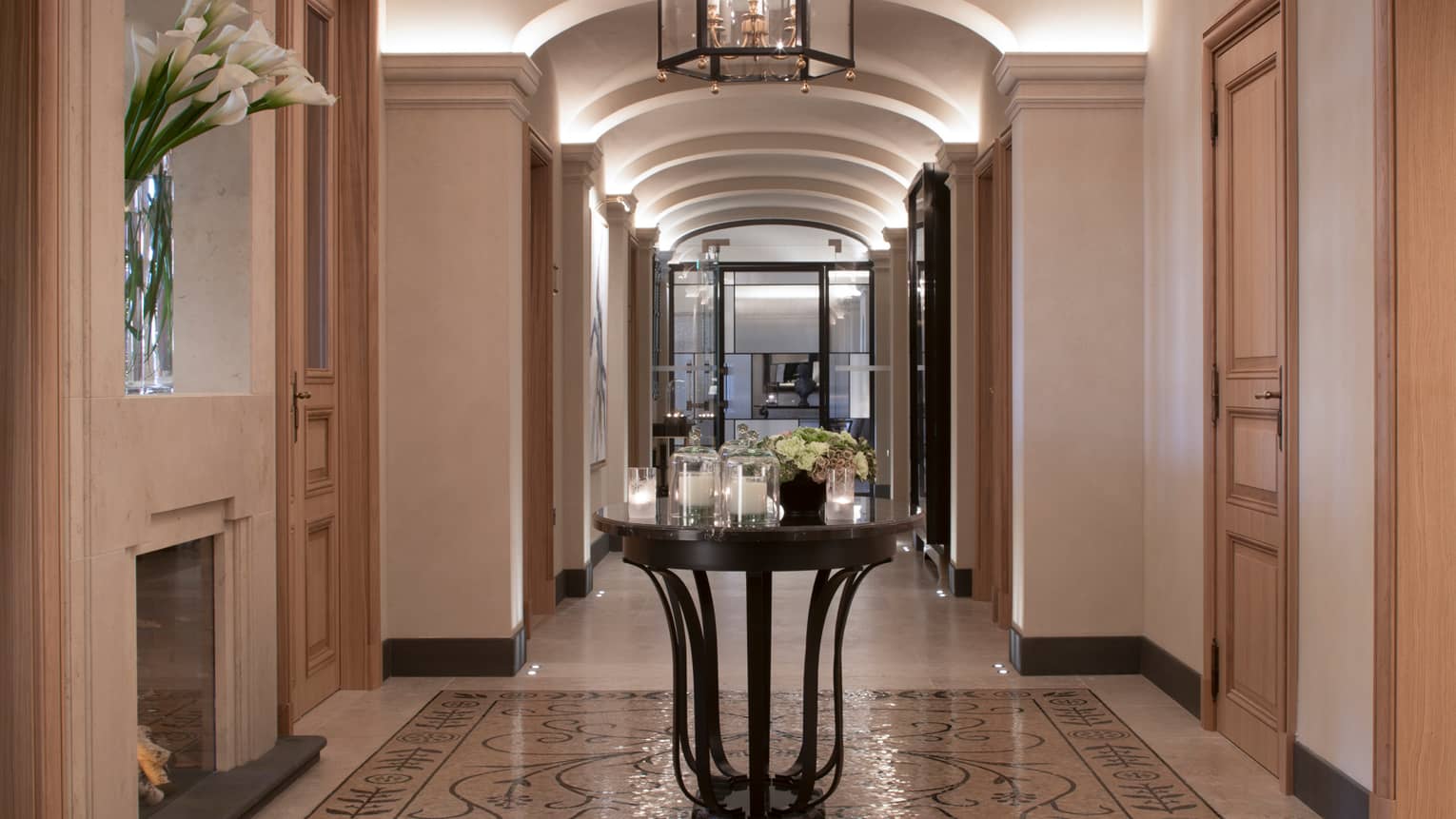 Hotel hallway with marble floors, round table with multiple white candles in glass votives, fresh flowers
