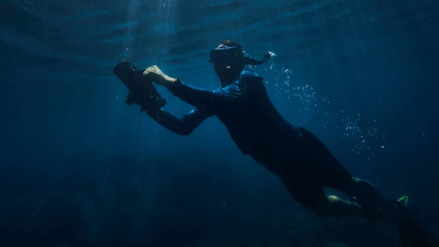 Person holding onto a water scooter underwater