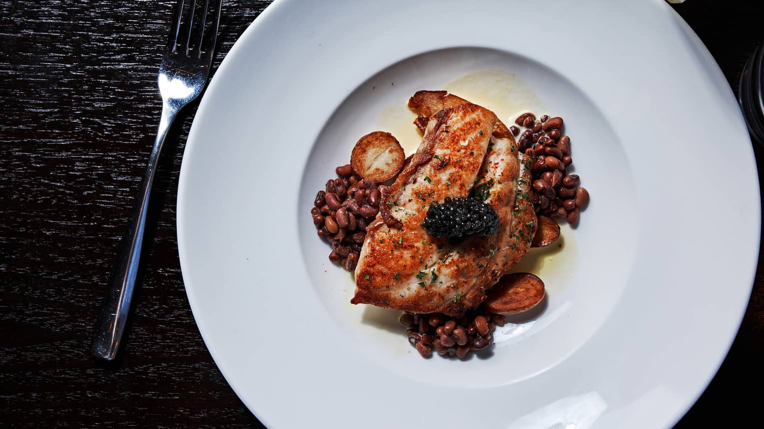 Seared grouper served with field peas, roasted potatoes and lemon sauce, garnished with caviar
