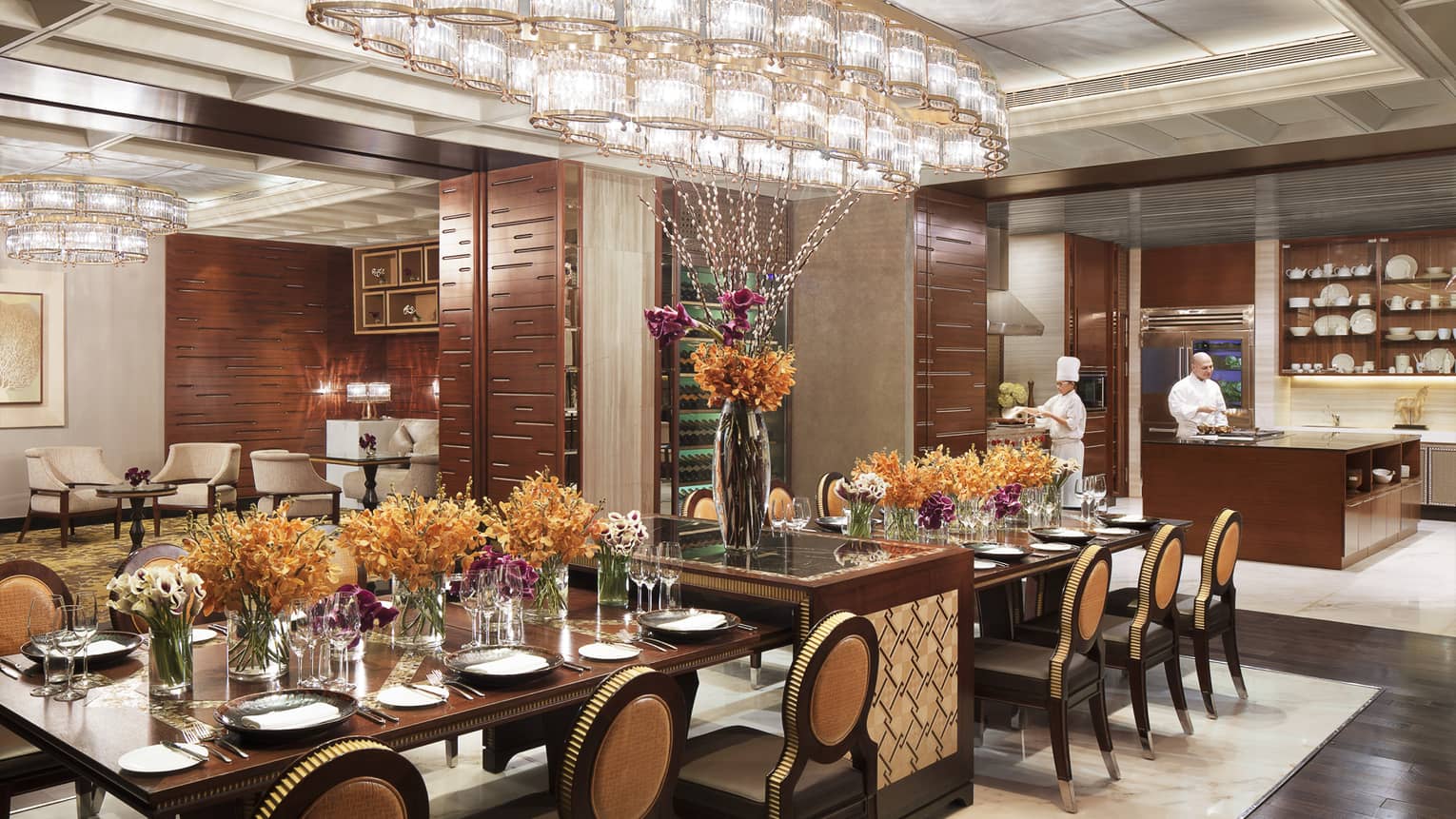 The Kitchen room, long private banquet dining table with orange flowers under rows of crystal lights 