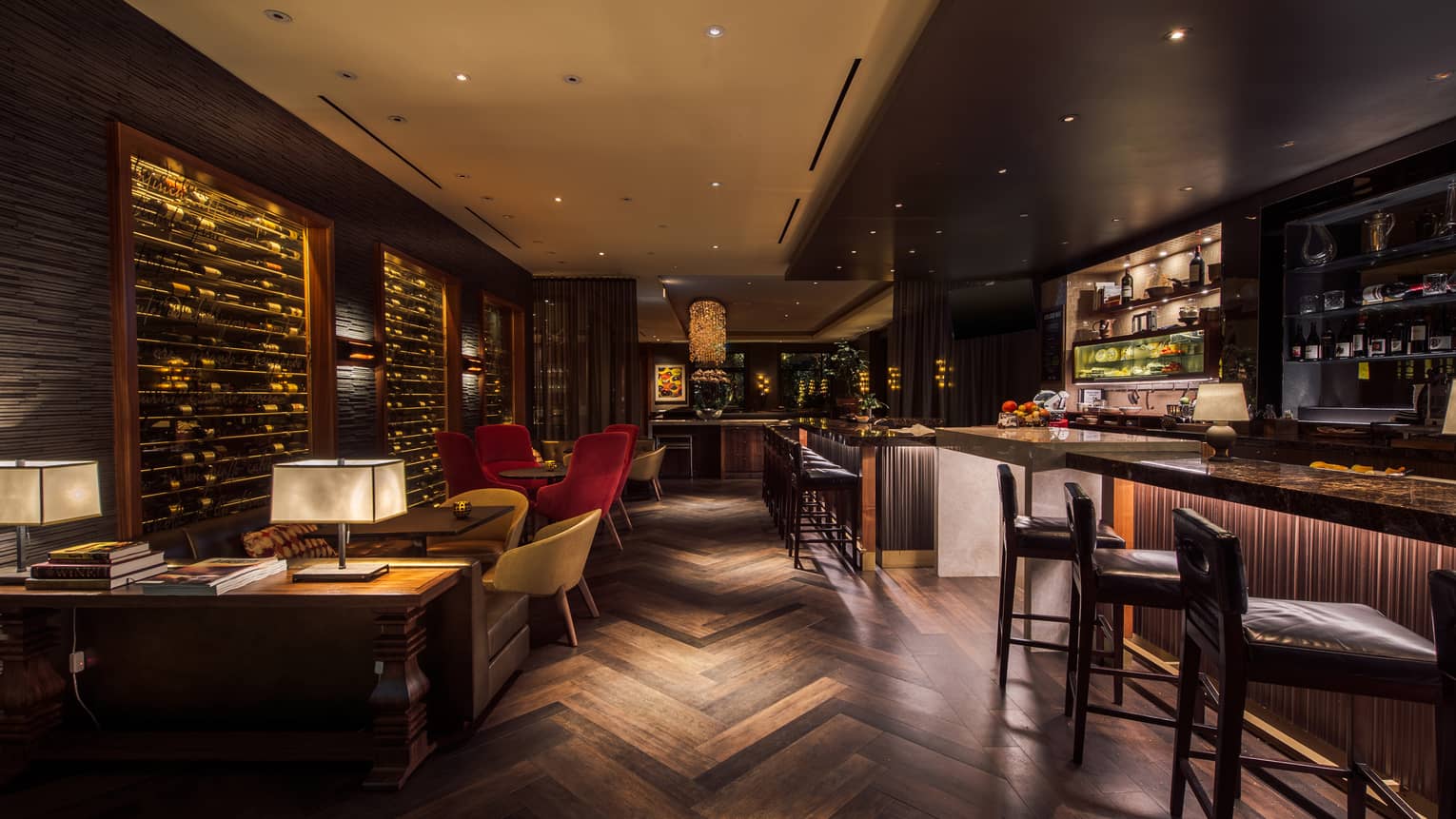 Dimly lit, indoor wine bar with geometric wooden floor, bar, wall of wine bottles