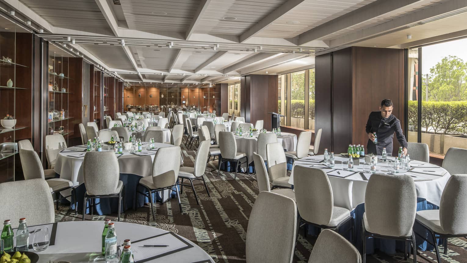 Hotel staff sets round banquet dining tables in event room