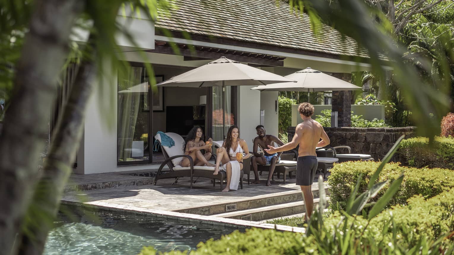 A group of four friends relax poolside at their Four-Bedroom Deluxe Residence