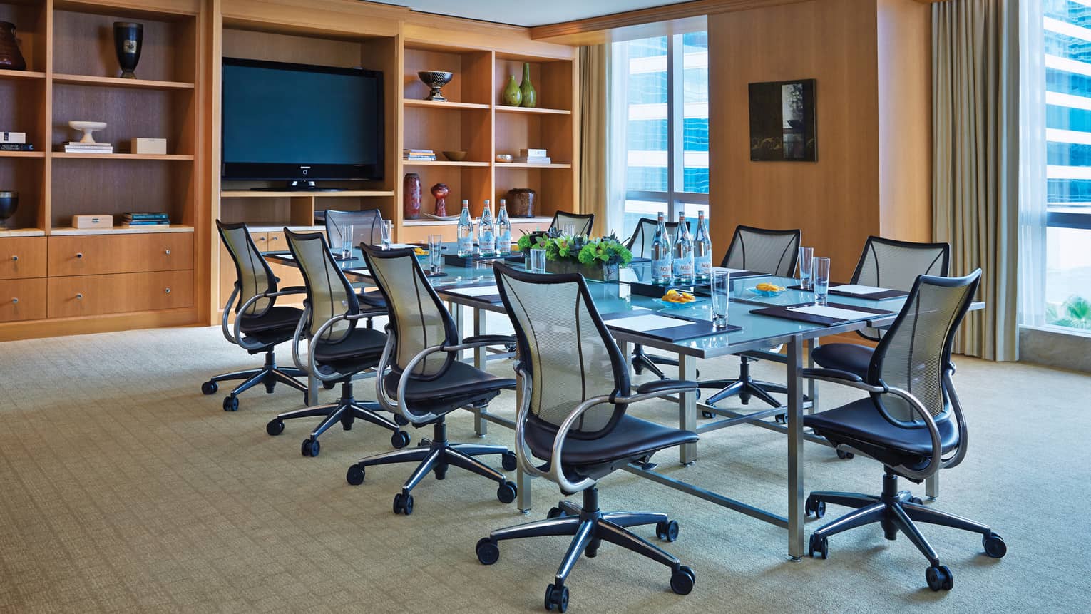 Swivel chairs line boardroom table in bright meeting room with shelves