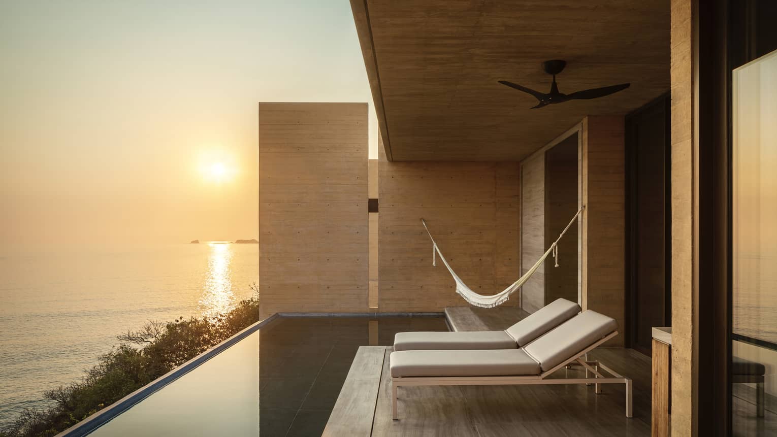 Poolside deck at sunset with lounge chairs, hammock and ocean views