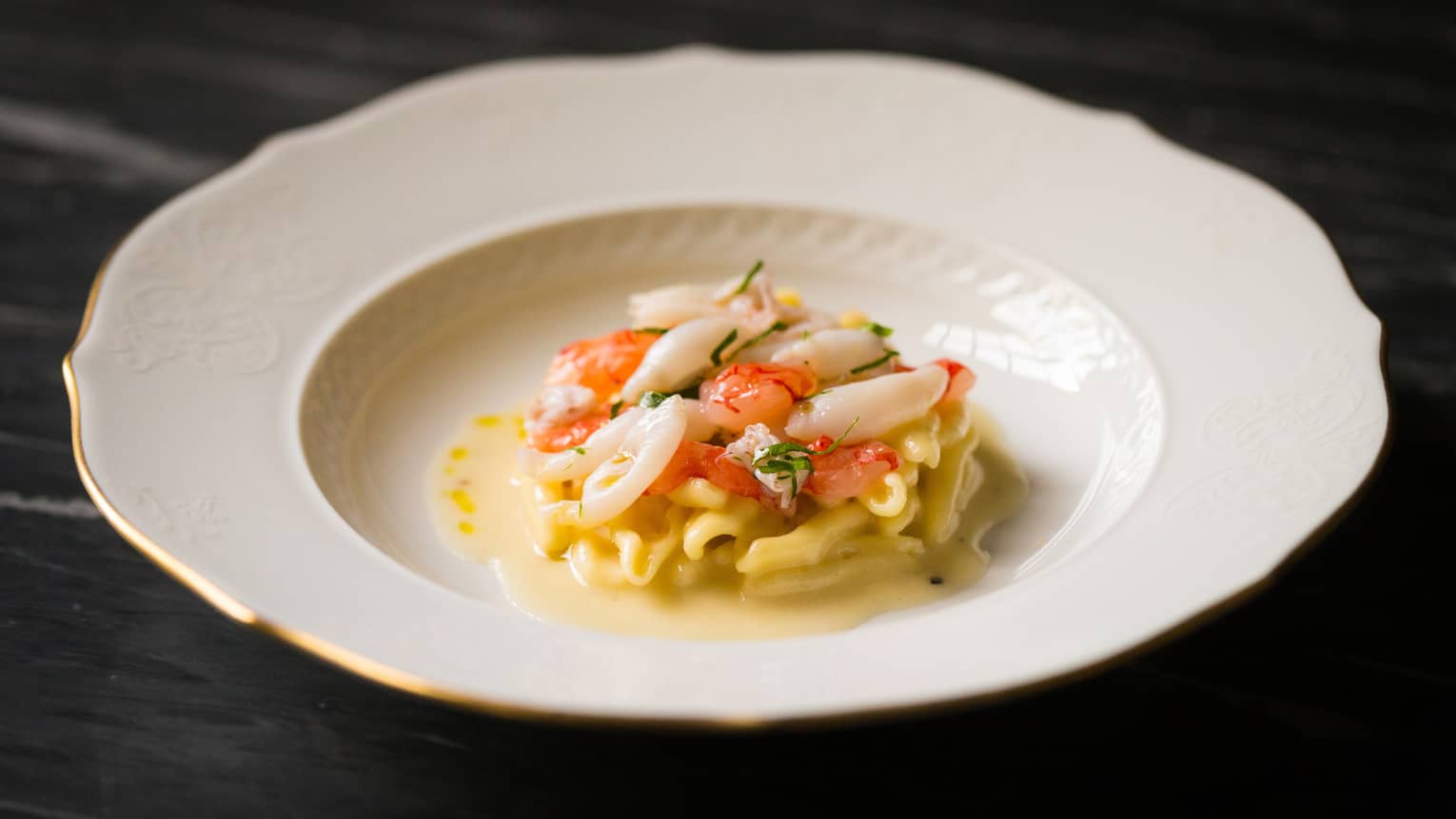 Seafood pasta in white dish on a dark table