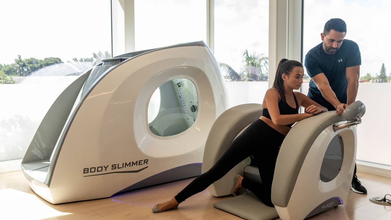 A woman in a machine with a wellness practitioner assisting her.