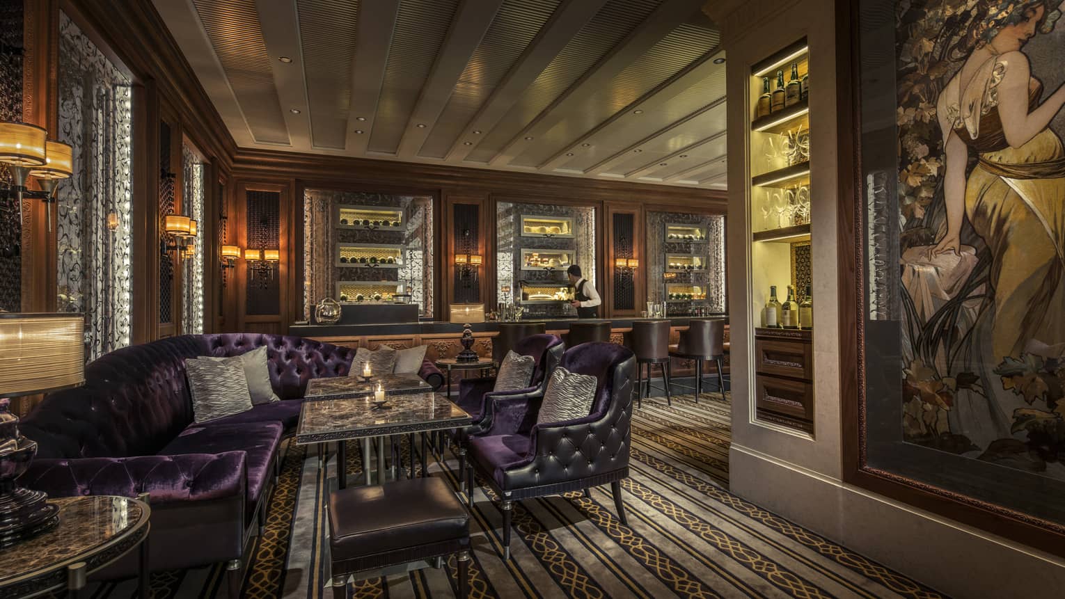 Dimly-lit Caprice Bar lounge with velvet purple sofas, leather armchairs, liquor on shelves with light
