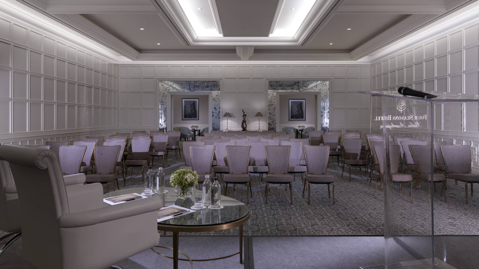 Glass podium, armchair facing rows of purple chairs in ballroom