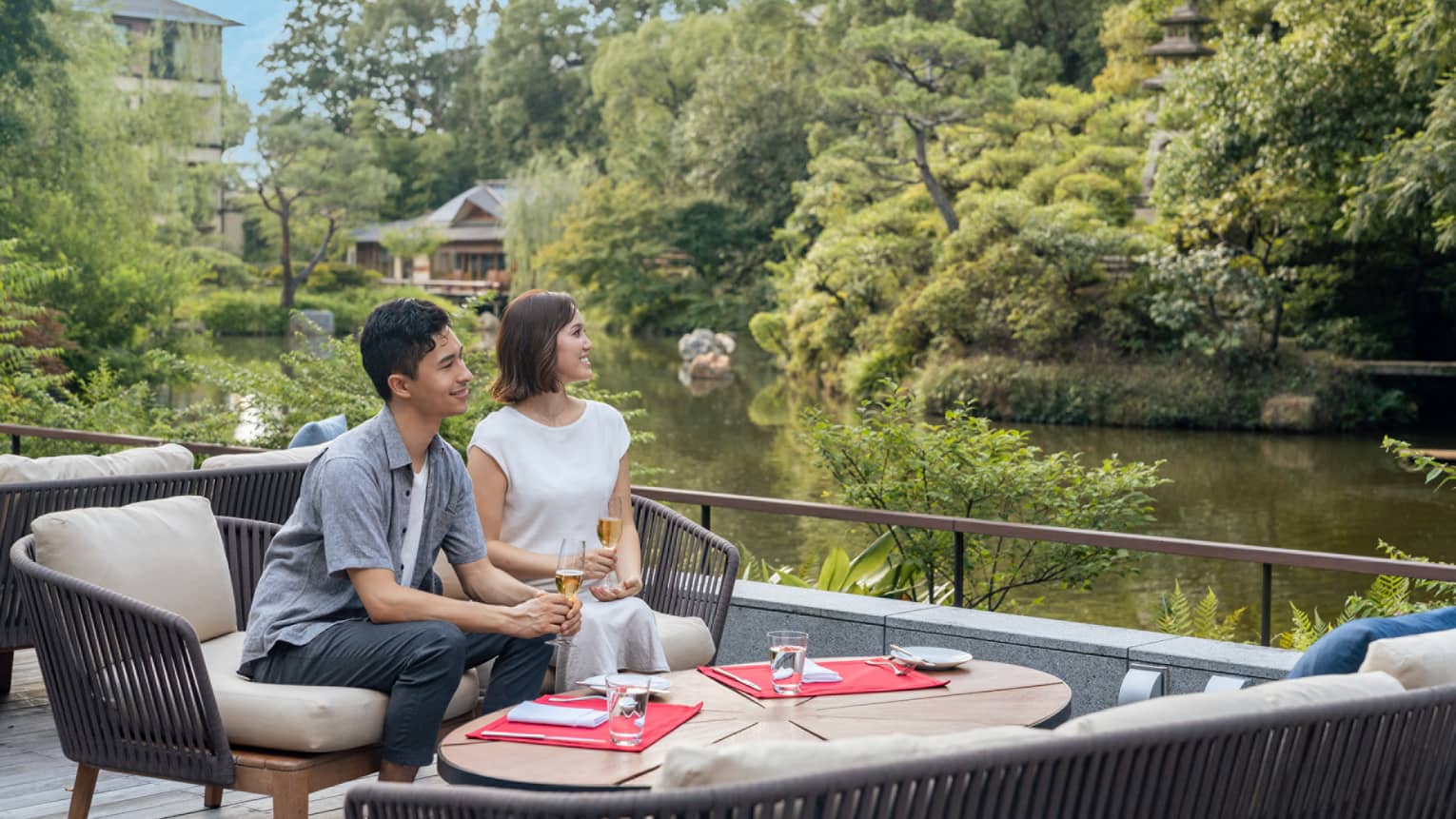 Couple relaxes with glasses of champagne on a riverside terrace