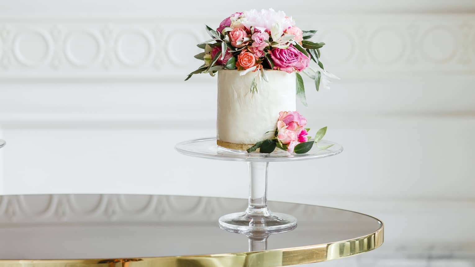 Elegant small white wedding cake topped with fresh pink and white roses 