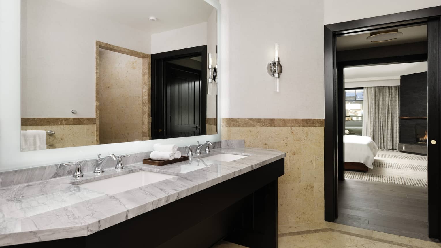 Bathroom with marble double vanity, beige limestone floors and walls