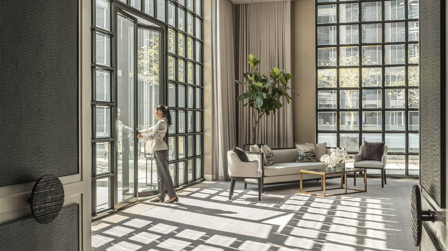 Studio II with cream-coloured carpet and matching furniture, green potted foliage, sunlight streaming in through floor-to-ceiling windows