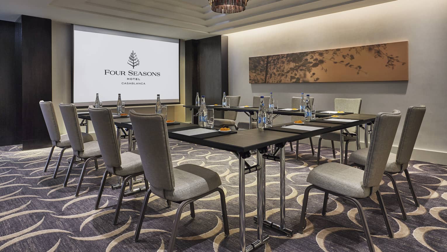 Business meeting room with large screen with Four Seasons logo, tables and chairs