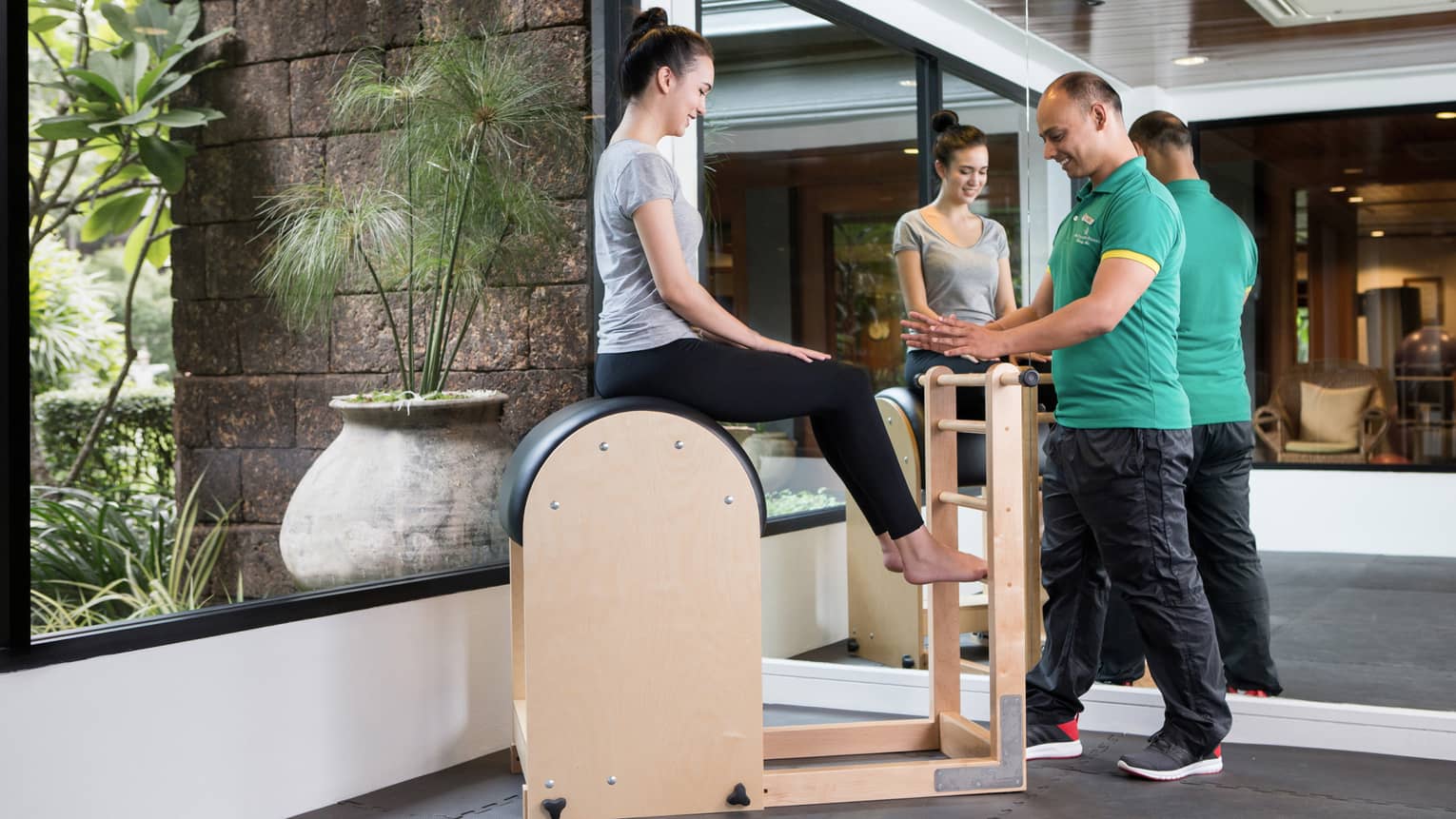 Four Seasons trainer assists woman balancing on pilates beam in Fitness Centre