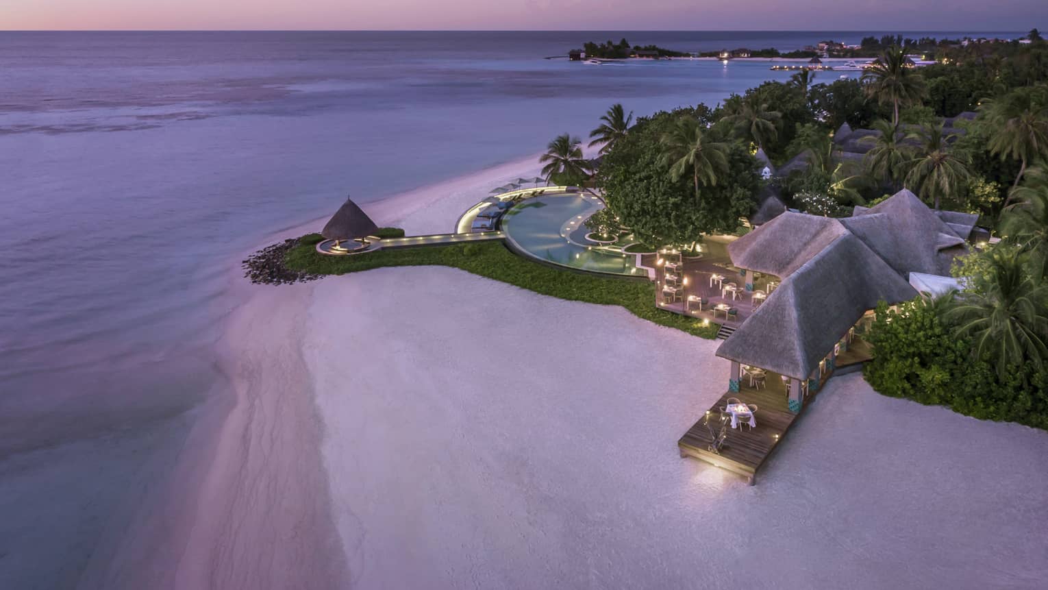 Aerial view of beach and Resort's illuminated deck with pool