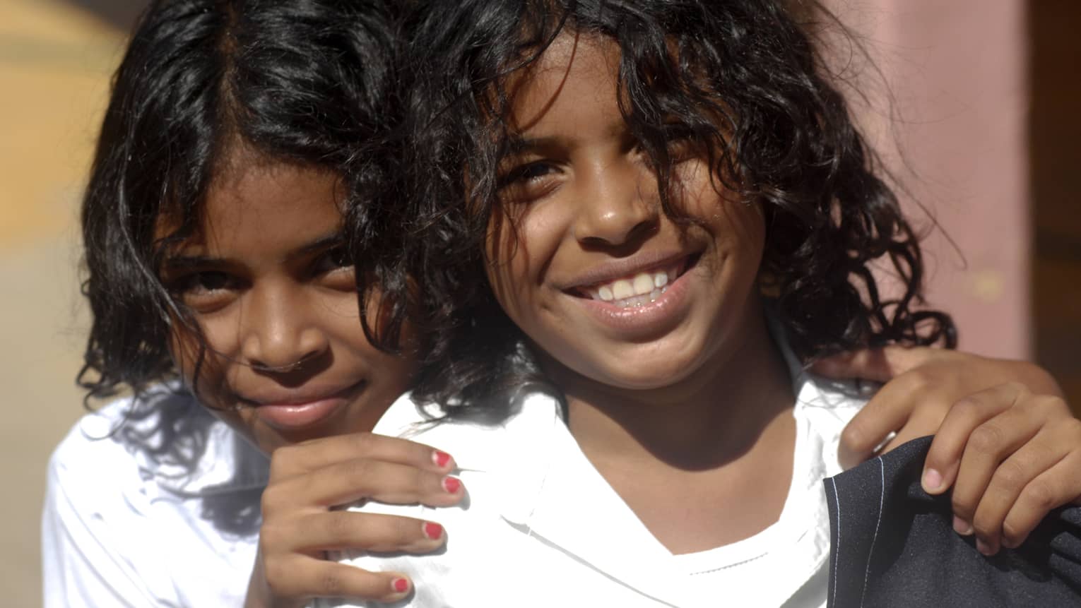 Close-up of two young smiling children, one with hands on the other's shoulders