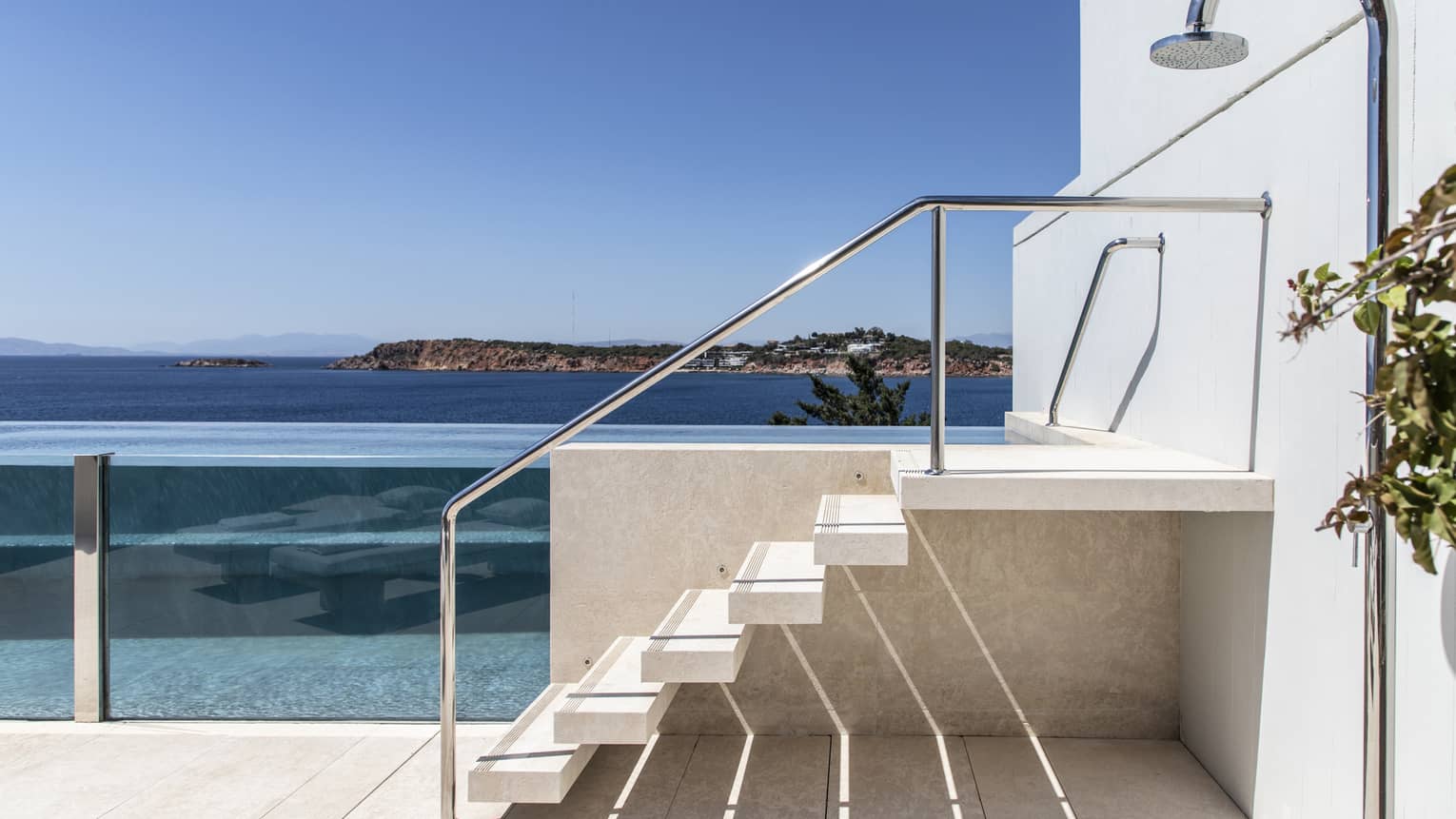 Six stairs lead to entrance of a raised, glass-enclosed pool on private patio with sea view