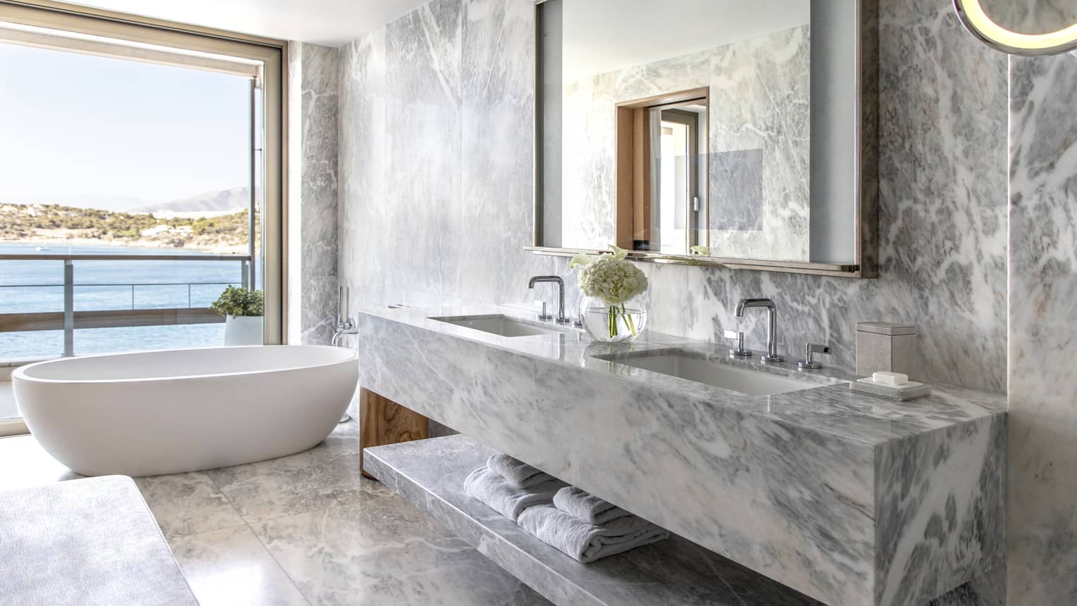 Bathroom with marble wall, vanity and floors, tub, open wall to the sea