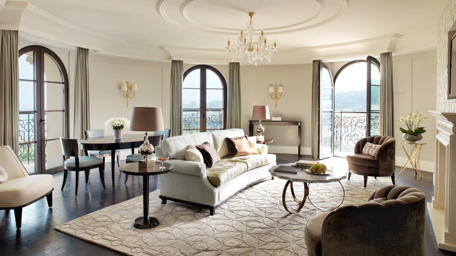 Two-Bedroom Suite circular living room in corner turret, French balcony doors, white sofa and area rug