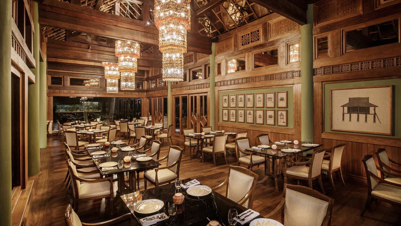 Long crystal chandeliers hang from high ceilings over KHAO indoor dining room with wood decor