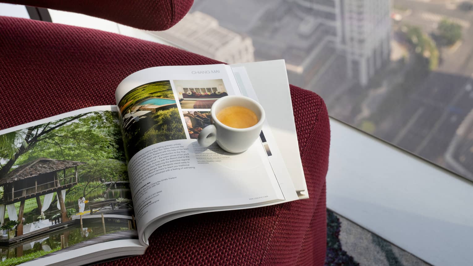 Four Seasons magazine and mug of tea sit on red chair at window