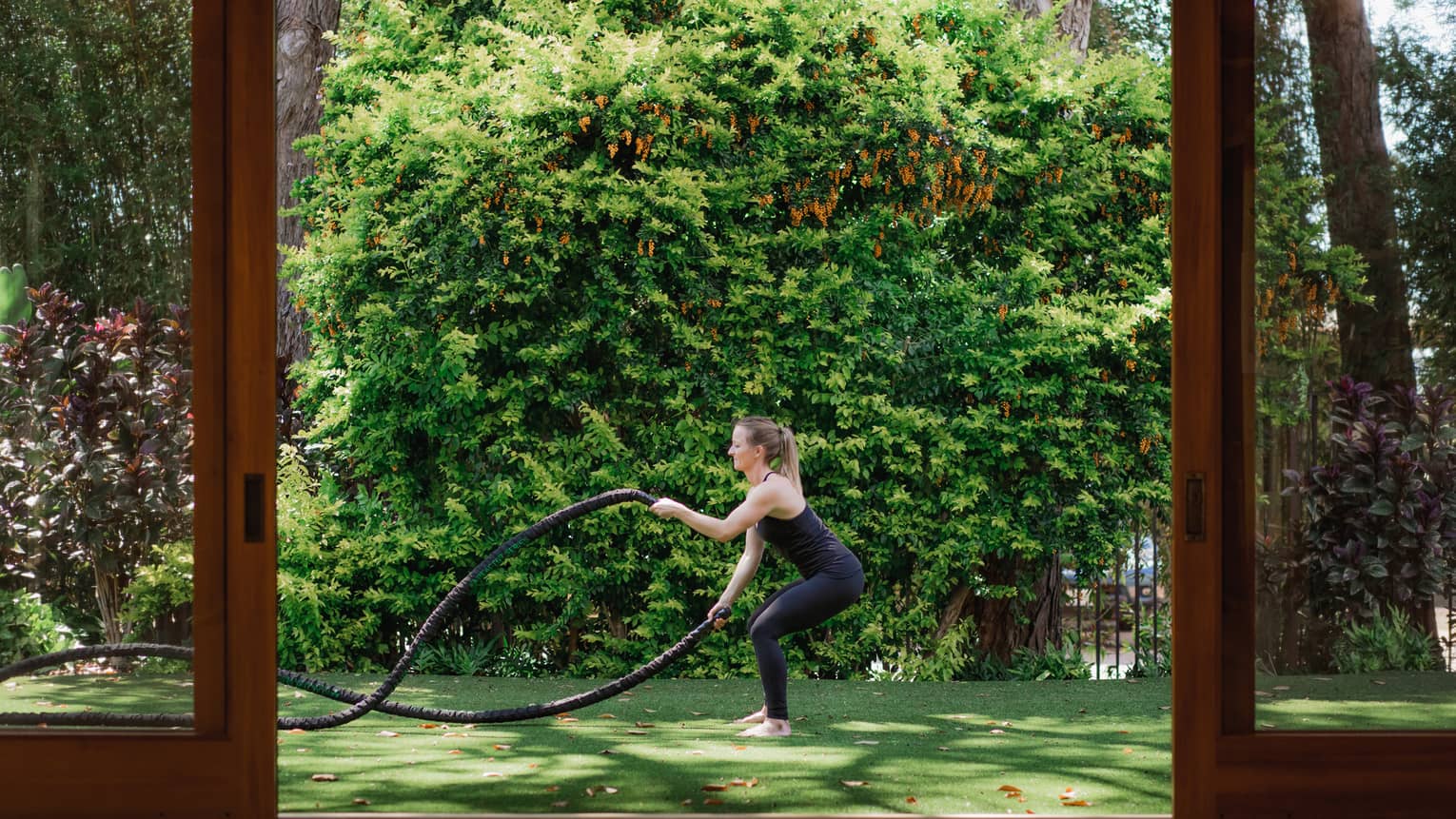 A woman does rope exercise outside on grass