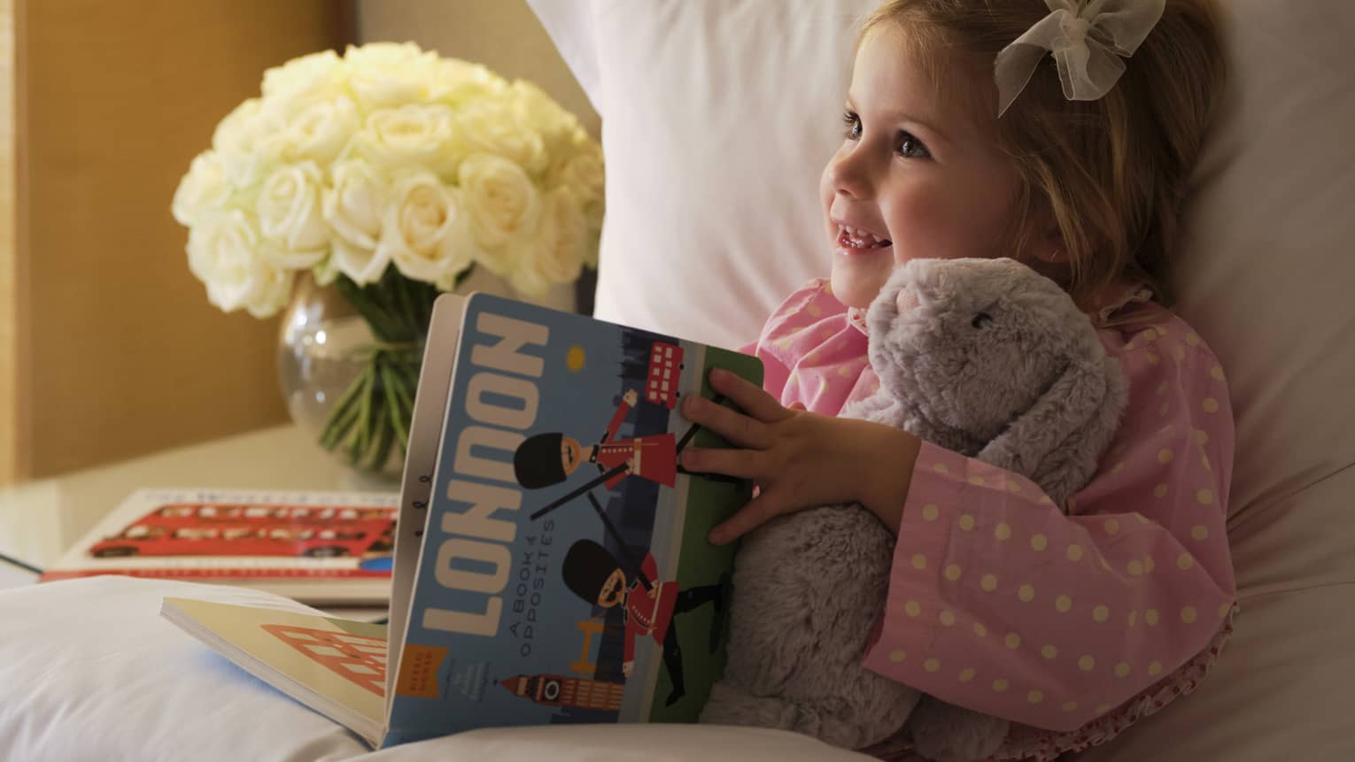 Little girl reads London picture book in bed