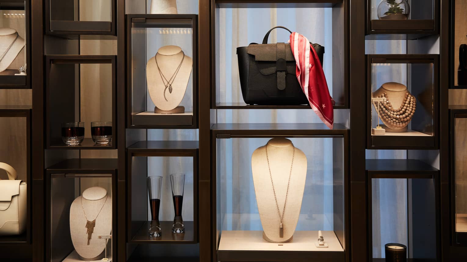 Boutique retail store shelf with designer necklaces, handbag, cocktail glasses 