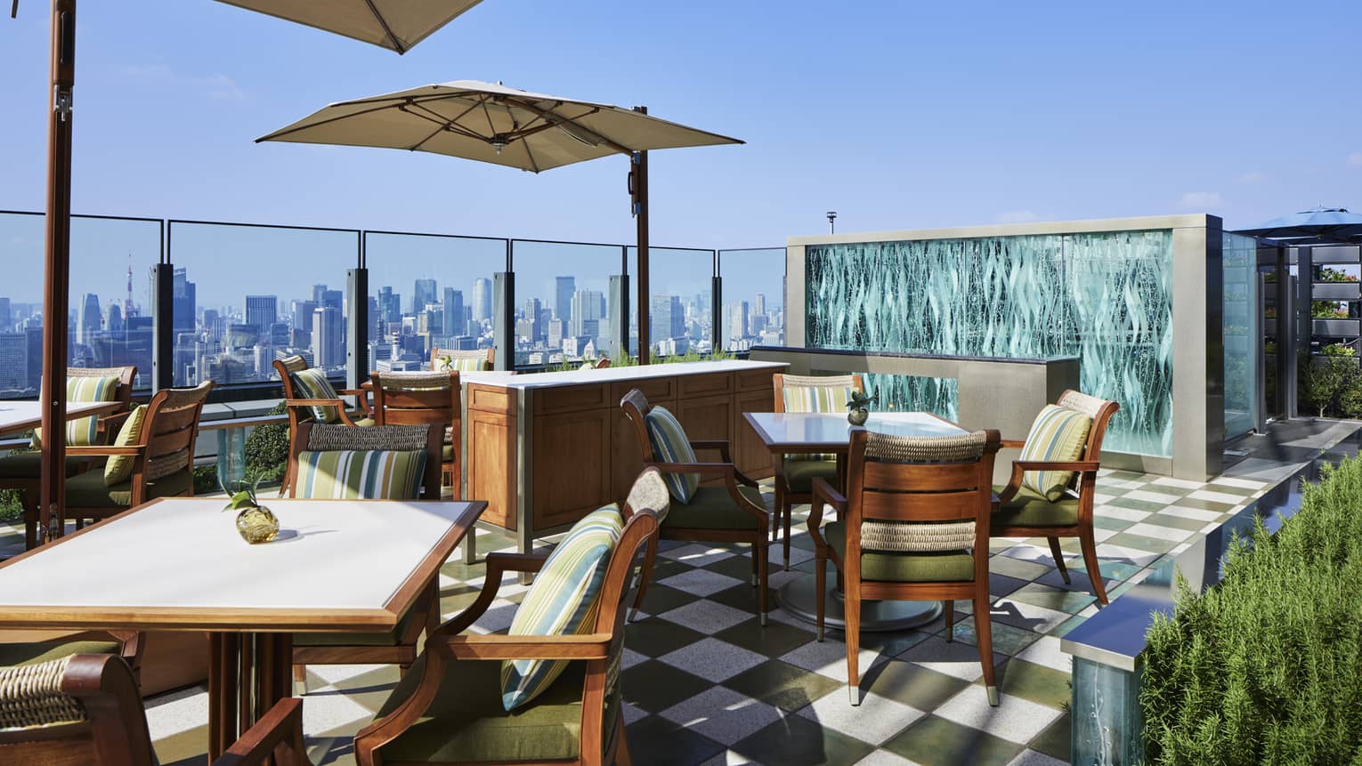 Outdoor rooftop terrace with umbrella-covered square tables and downtown views