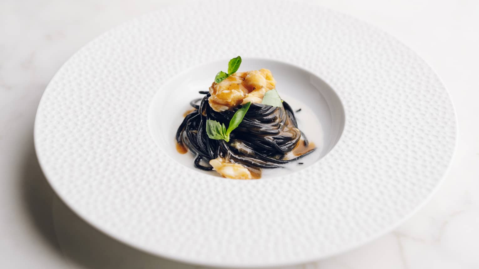 Black Spaghetti al Nero Topped with Blue Crab on white plate