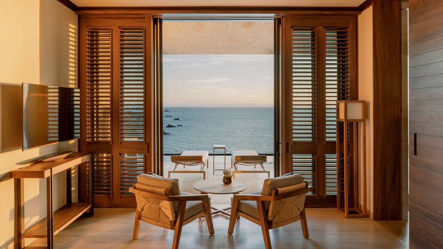 Sitting area with two arm chairs and small table facing outwards to ocean-view terrace