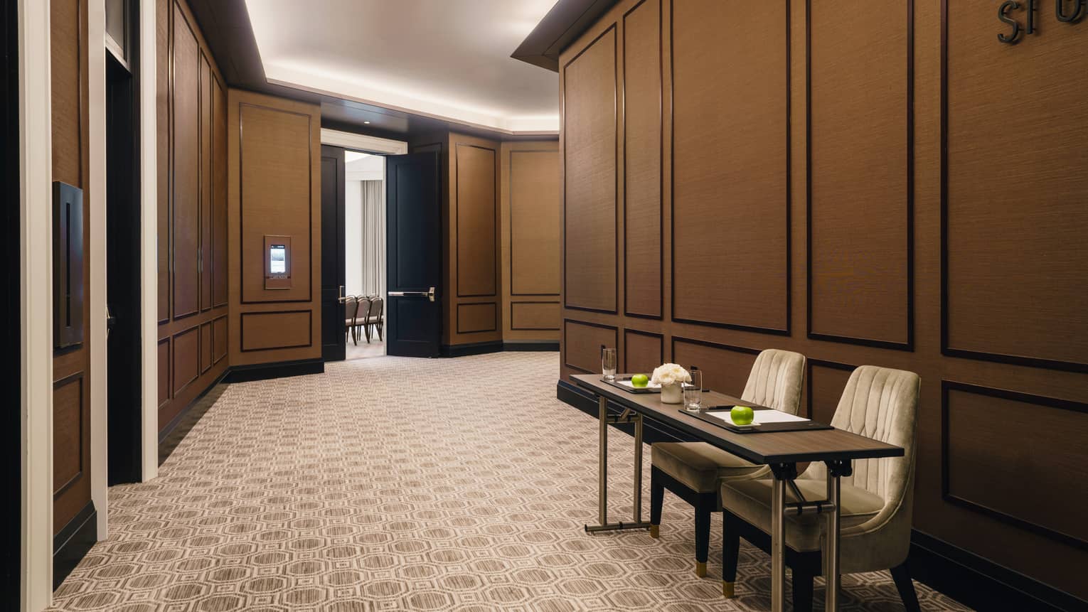 St. Germain foyer with two-person table, uplighting, tan carpet, doors leading to meeting rooms 