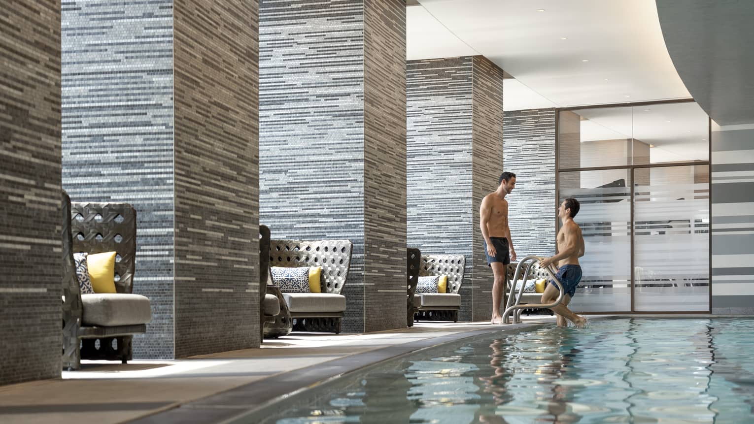 Two men near an indoor pool.