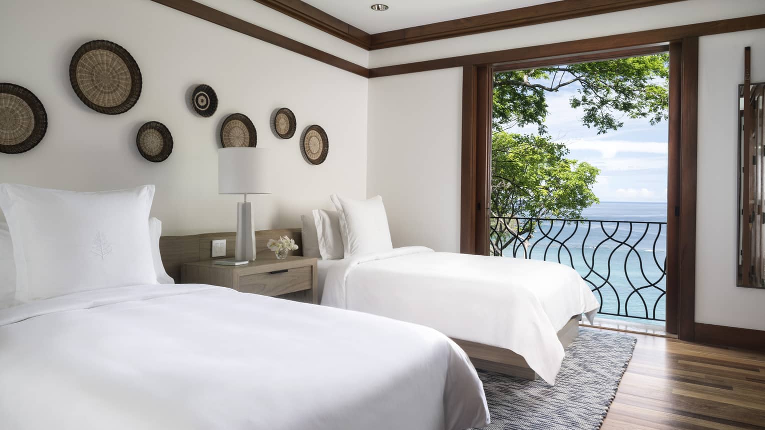 Twin beds with white linens beside open door to iron terrace, ocean views 