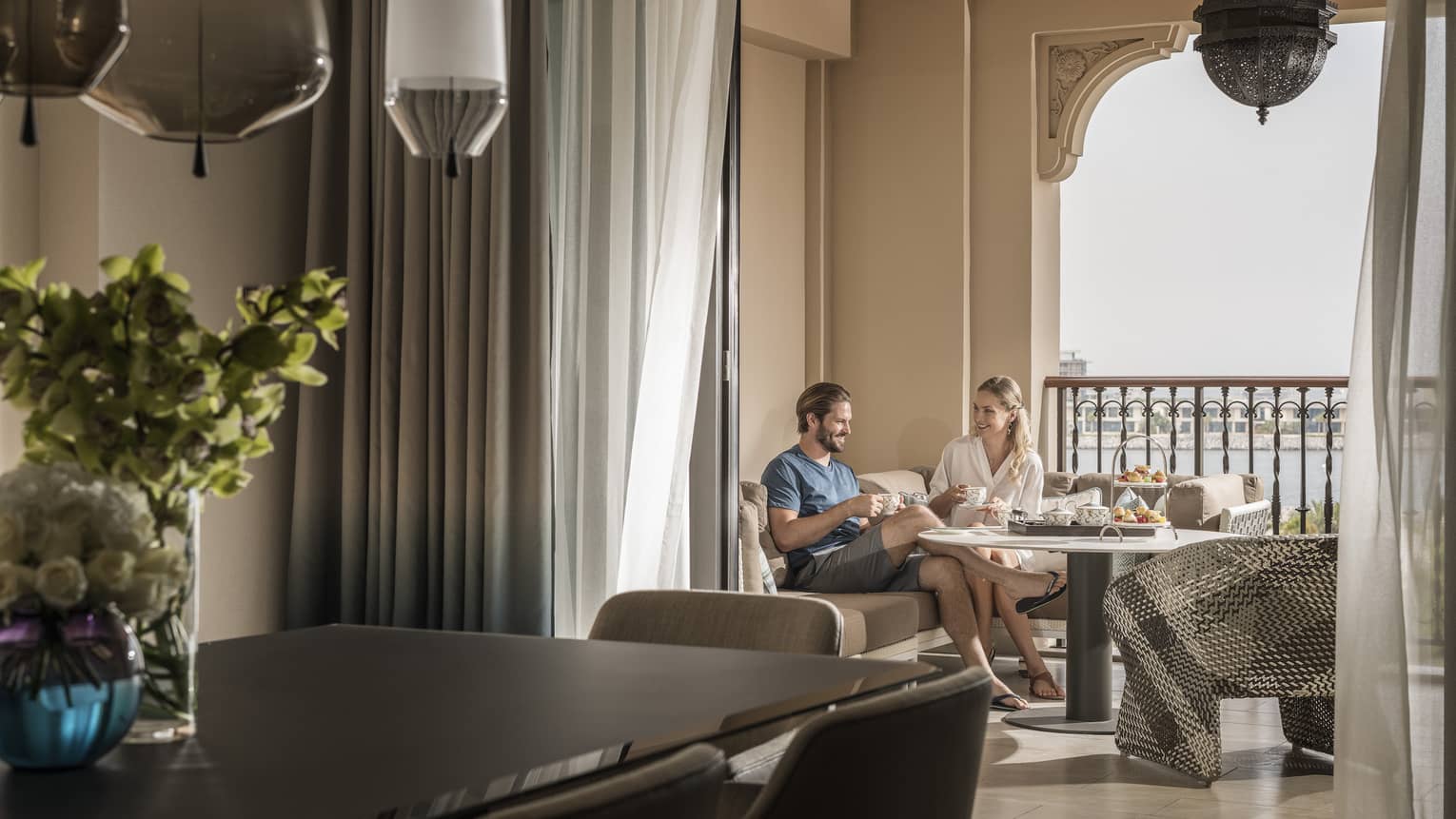 Hotel suite dining table in front of couple enjoying breakfast on covered balcony