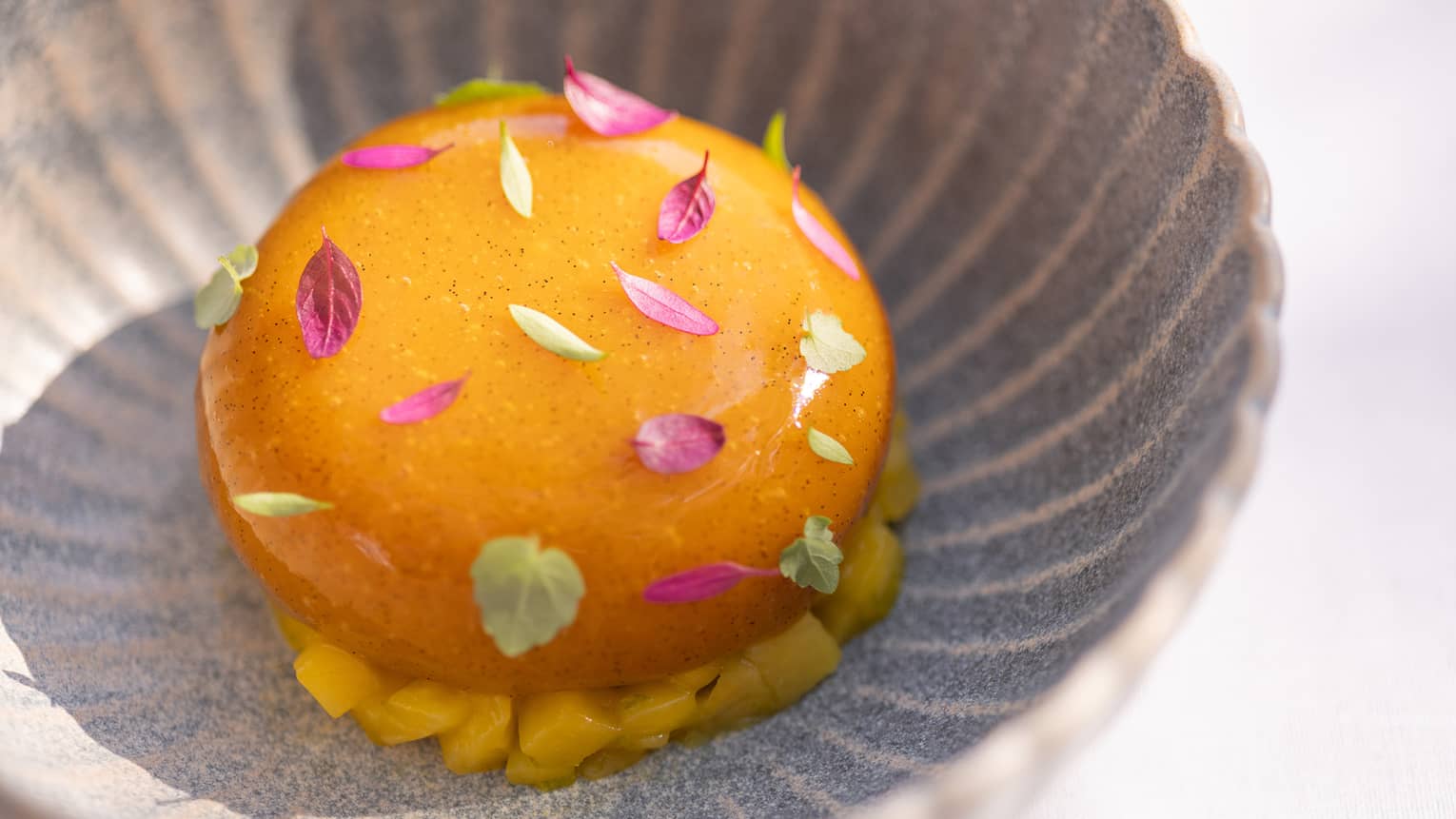 Mango and Yuzu Baba Garnished with Edible Fuchsia and Green Mini Leaves