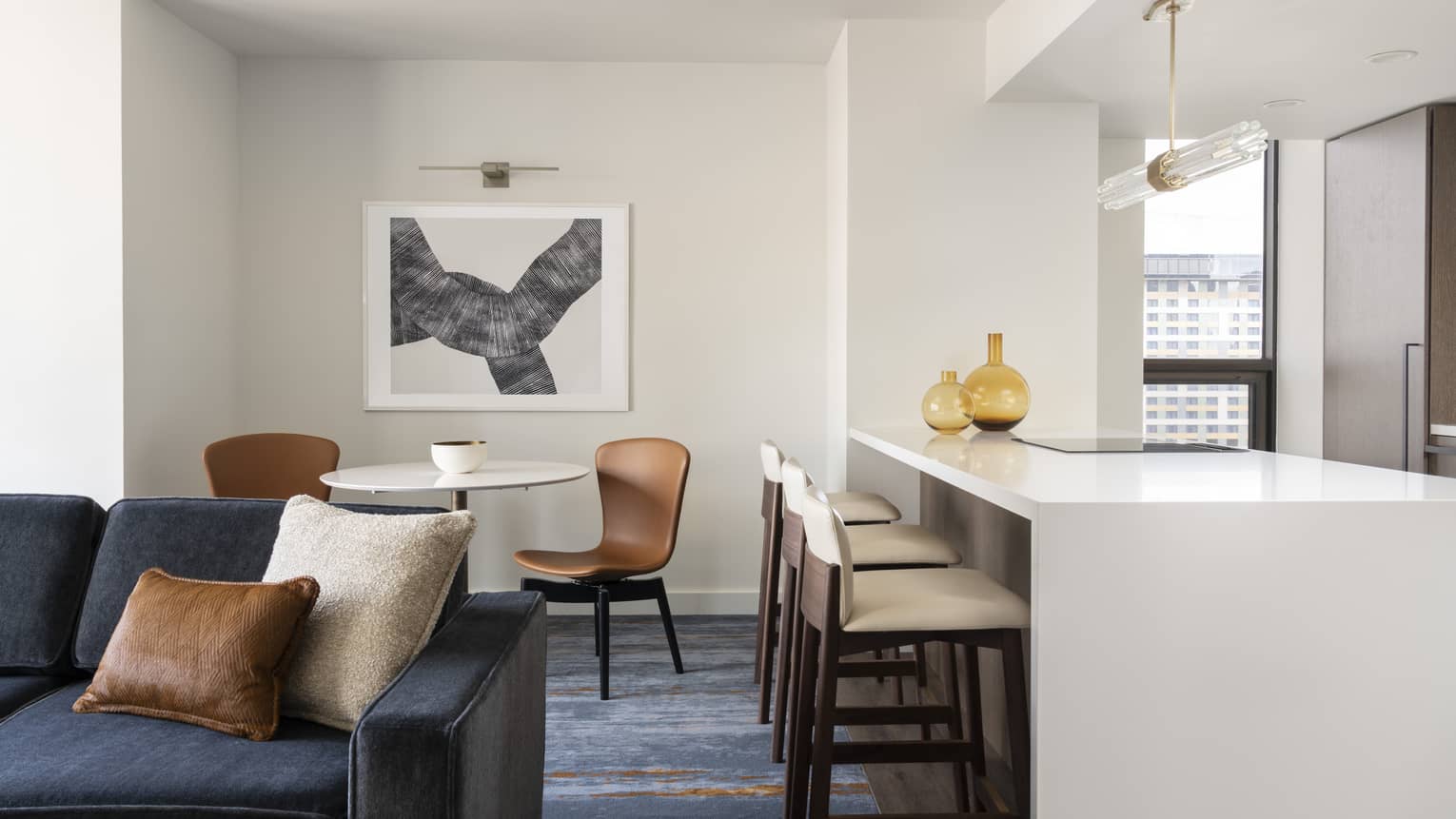 One-bedroom Residential Suite living area, dining area and kitchen with dark blue accents and bar stools