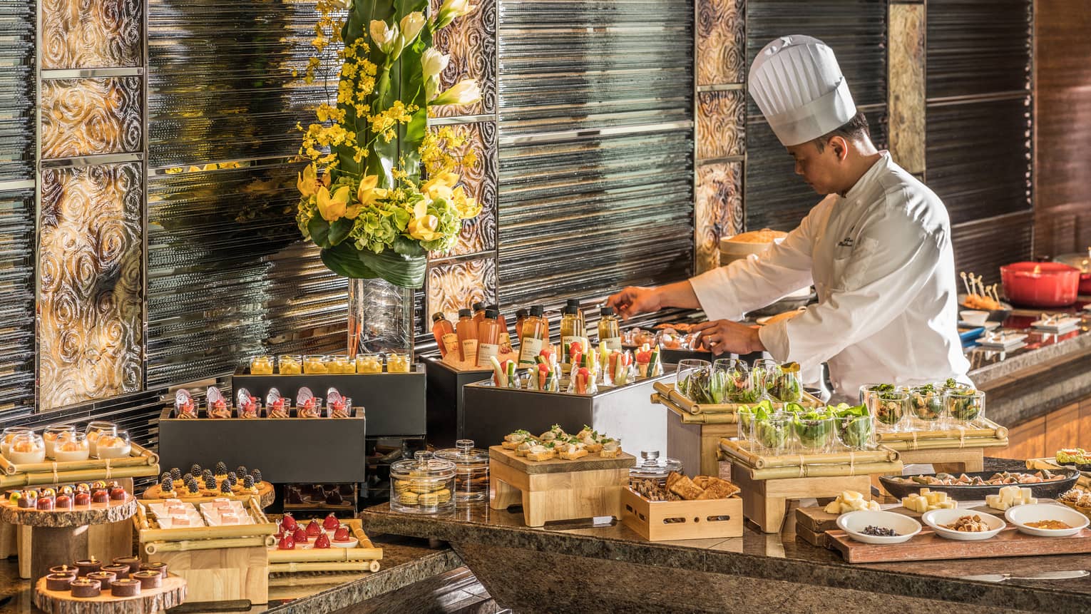 Chef in chef's uniform arranging bottled drinks and a variety of buffet dishes