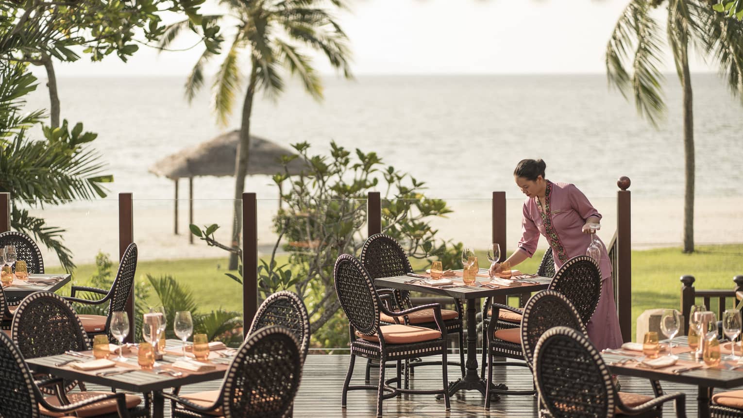 A server at Ikan Ikan sets a table on the outdoor terrace overlooking the beach