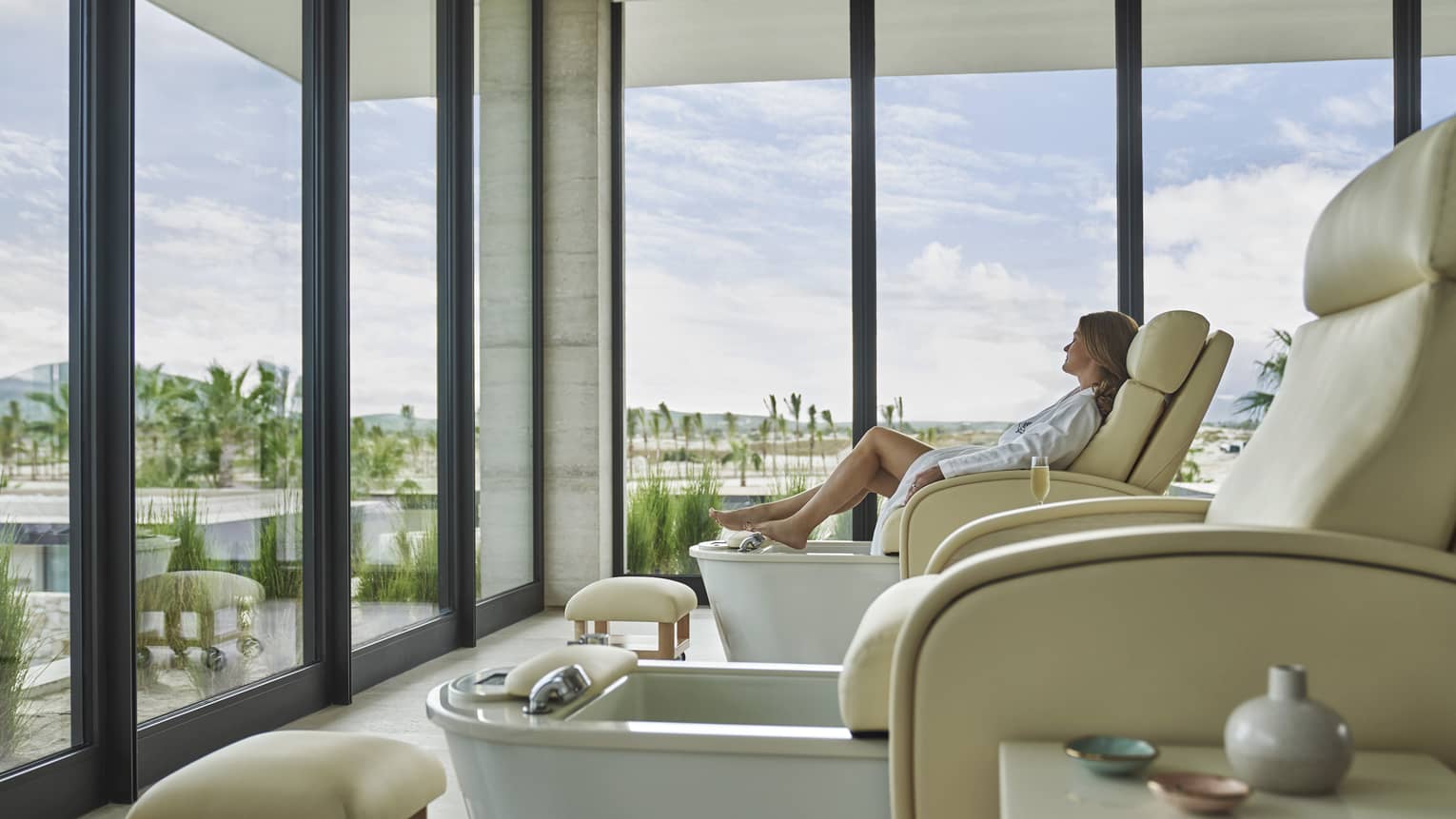 A woman in a pedicure chair looking out of large windows.