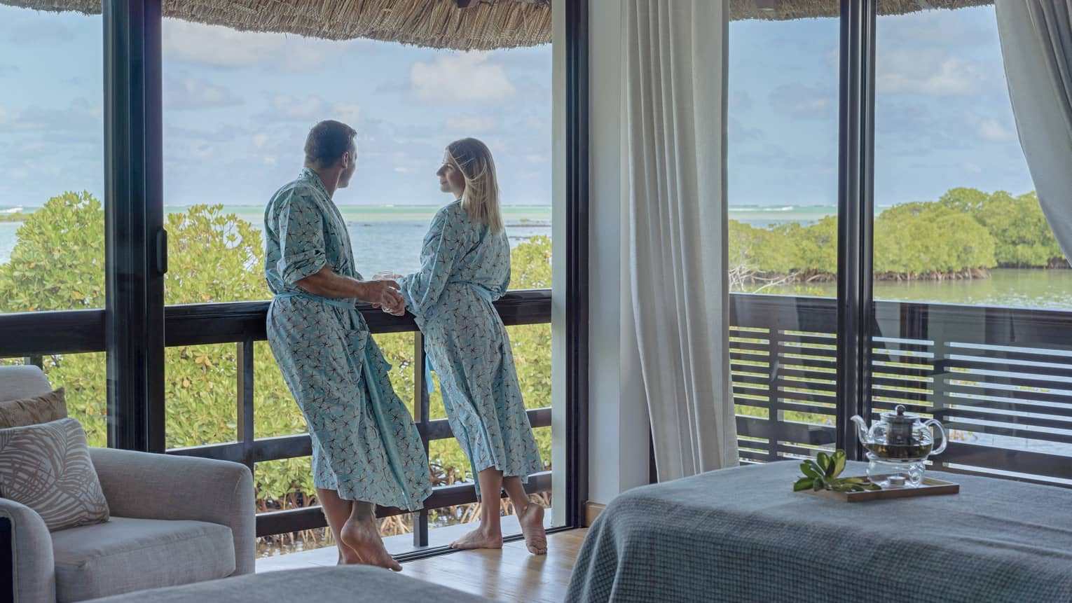 Couple in matching bathrobes stand on the balcony of their Spa treatment room
