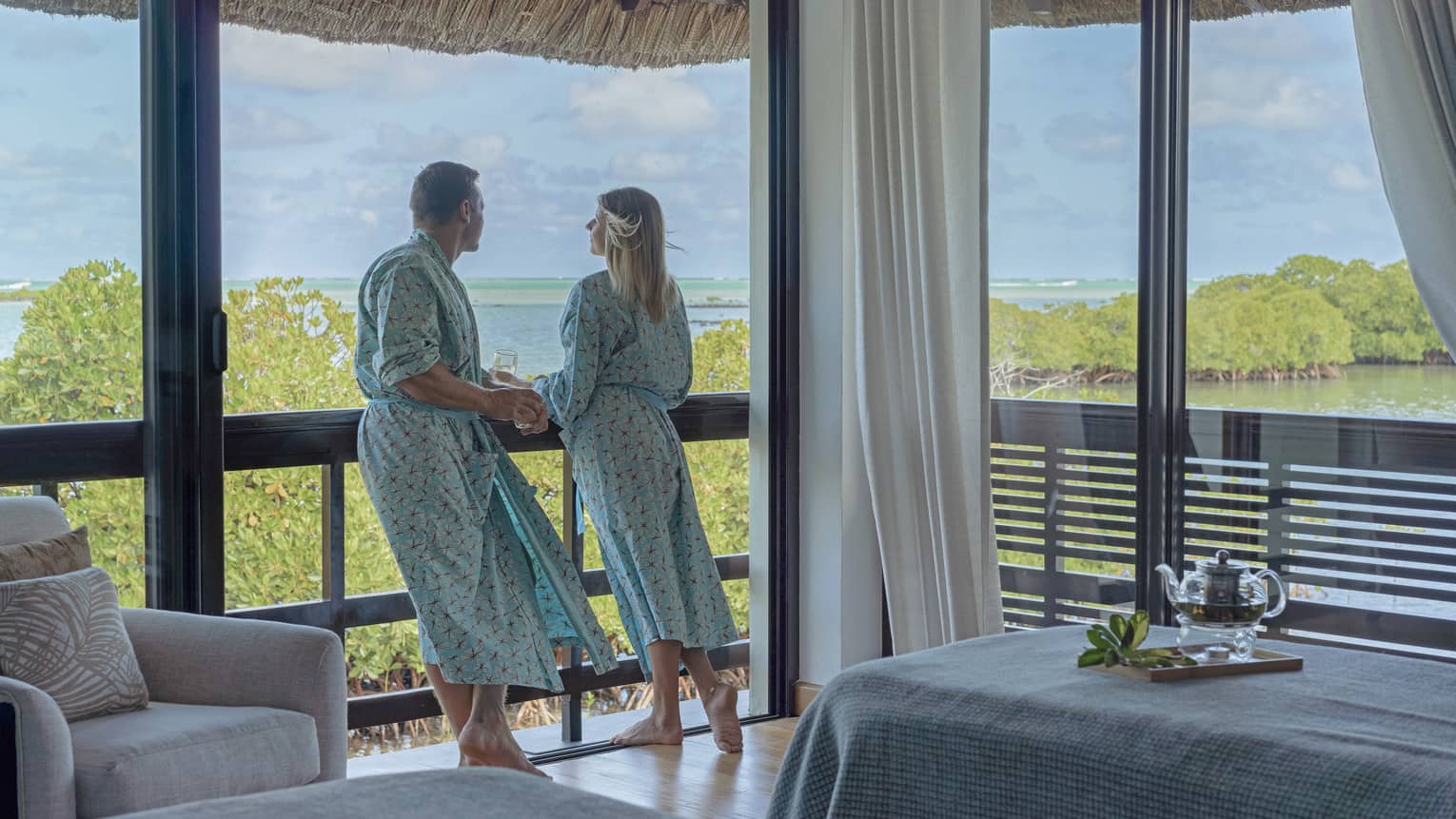 Couple in matching robes stand on the balcony of their open-air Spa treatment room