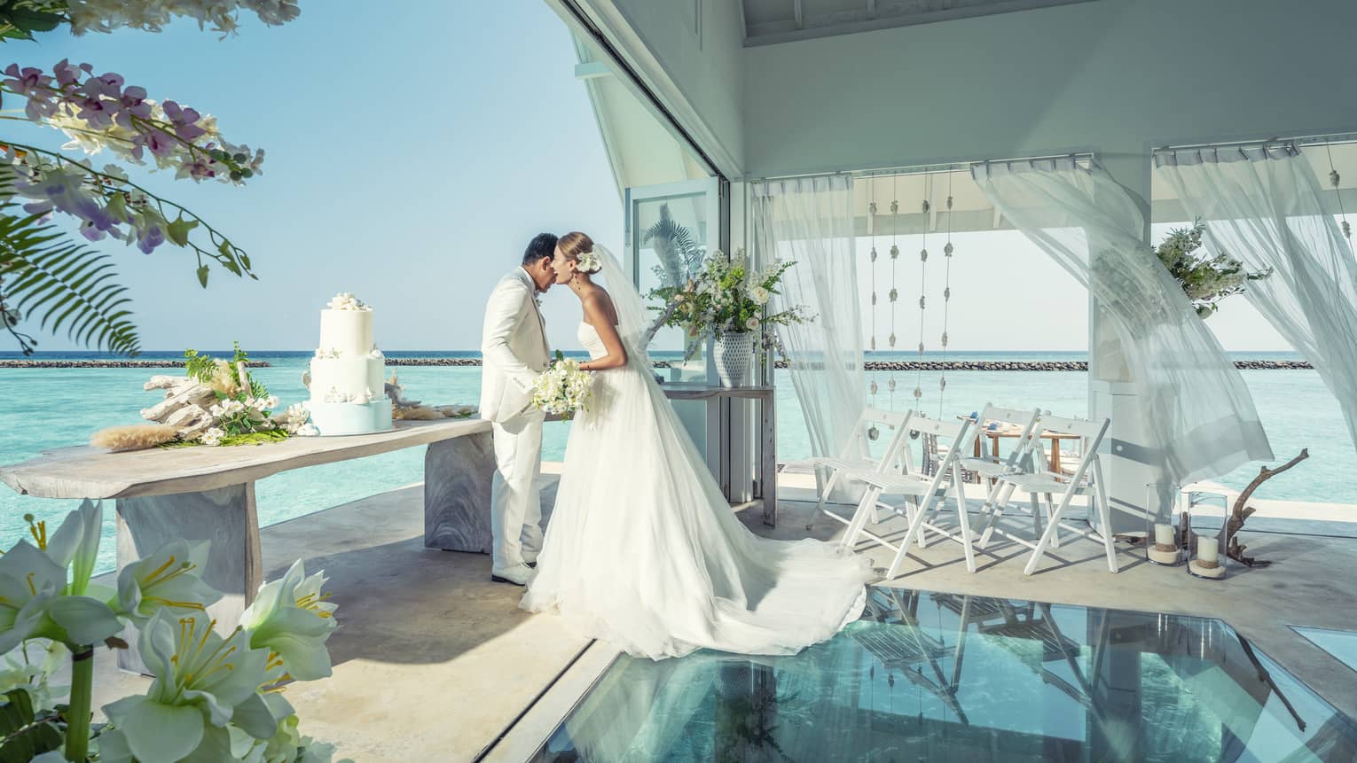Bride and groom embrace in overwater wedding bungalow