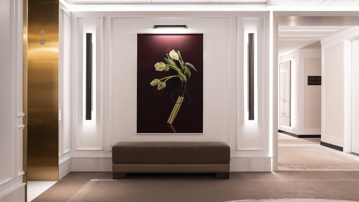 White grand foyer with over-sized painting of white flowers with purple background, below a brown sofa