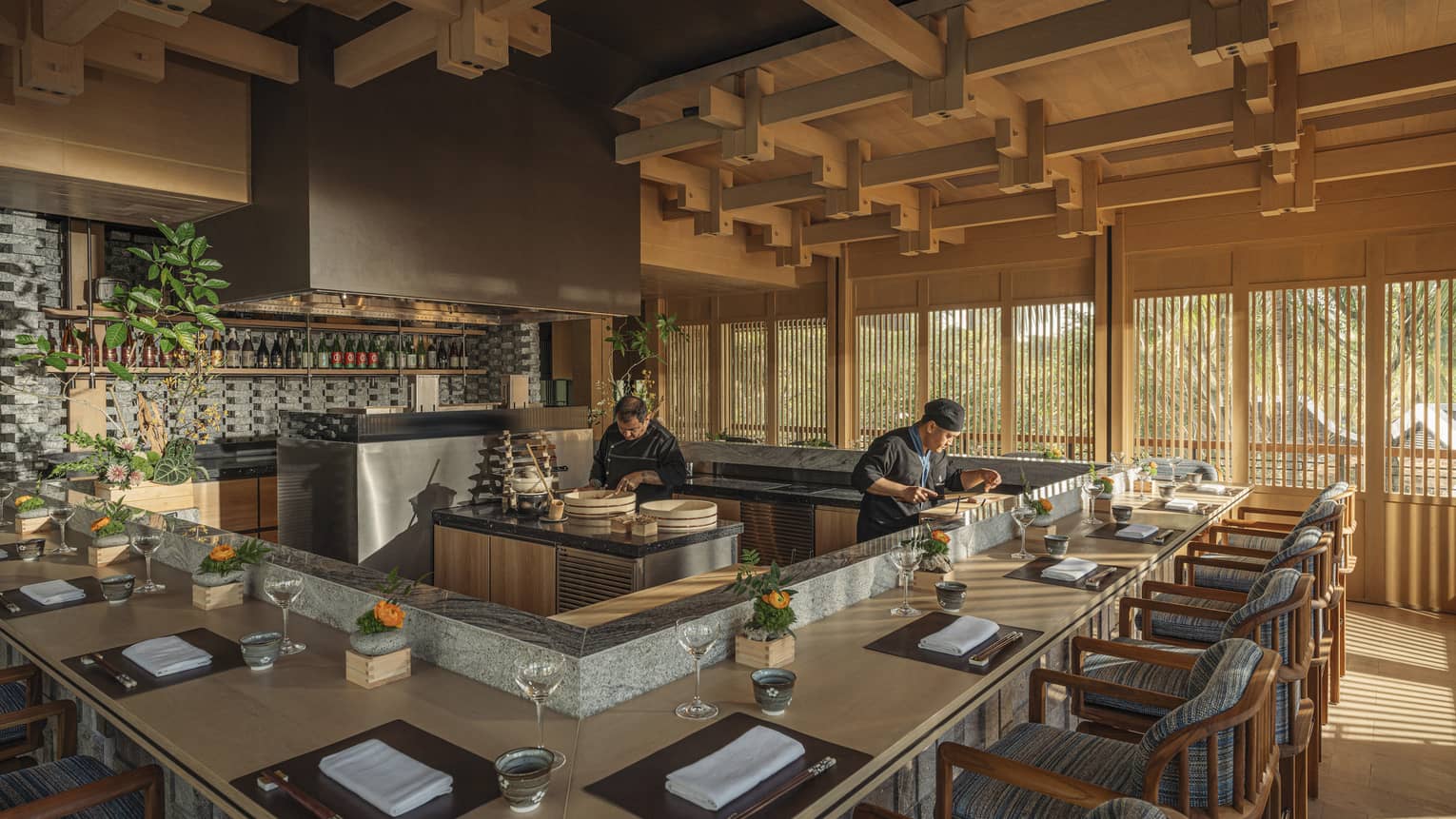 Two chefs prepare dishes behind omakase counter at bright and airy NAYUU restaurant