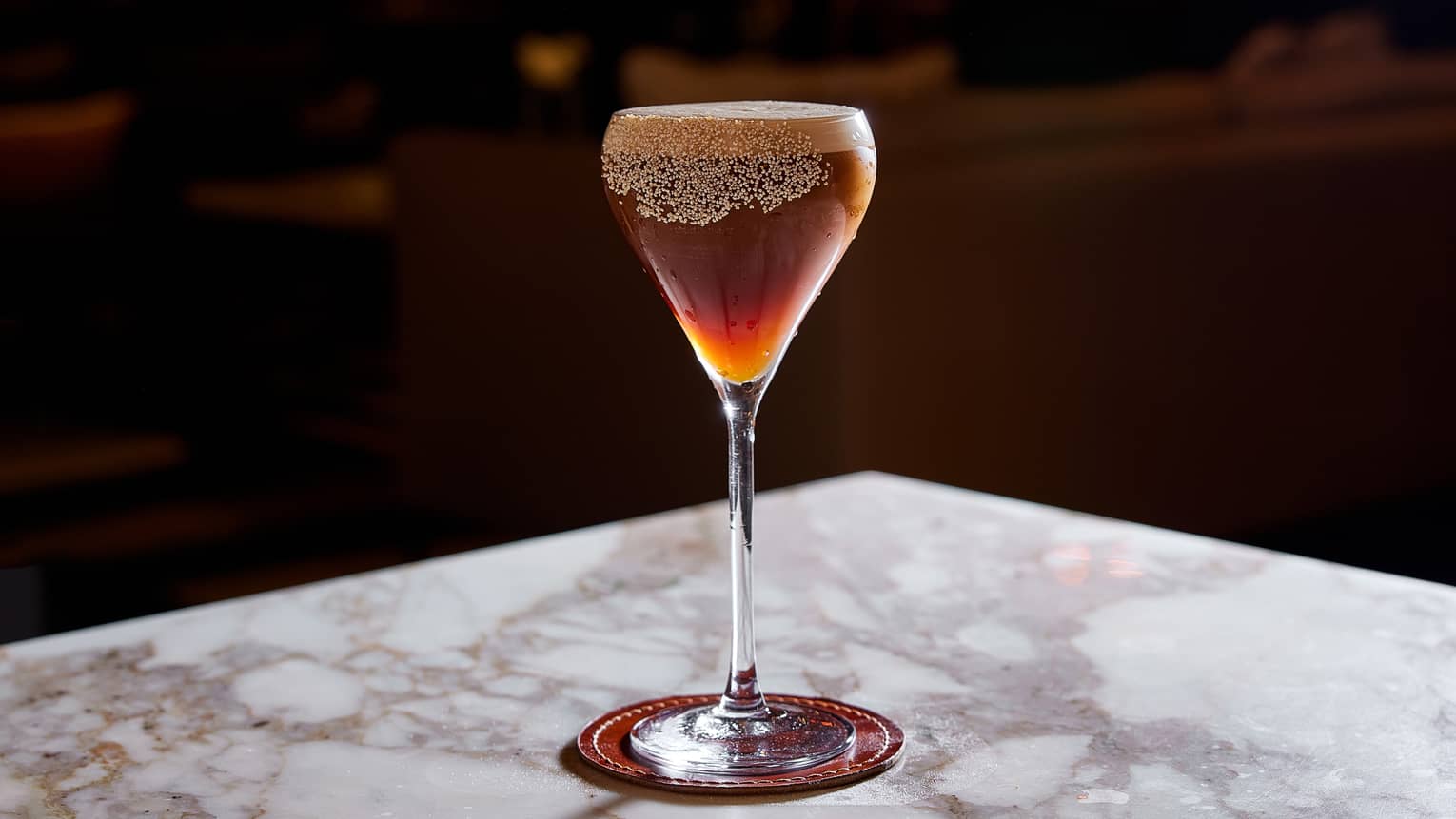Dark brown and orange coffee cocktail topped with foam in wine glass