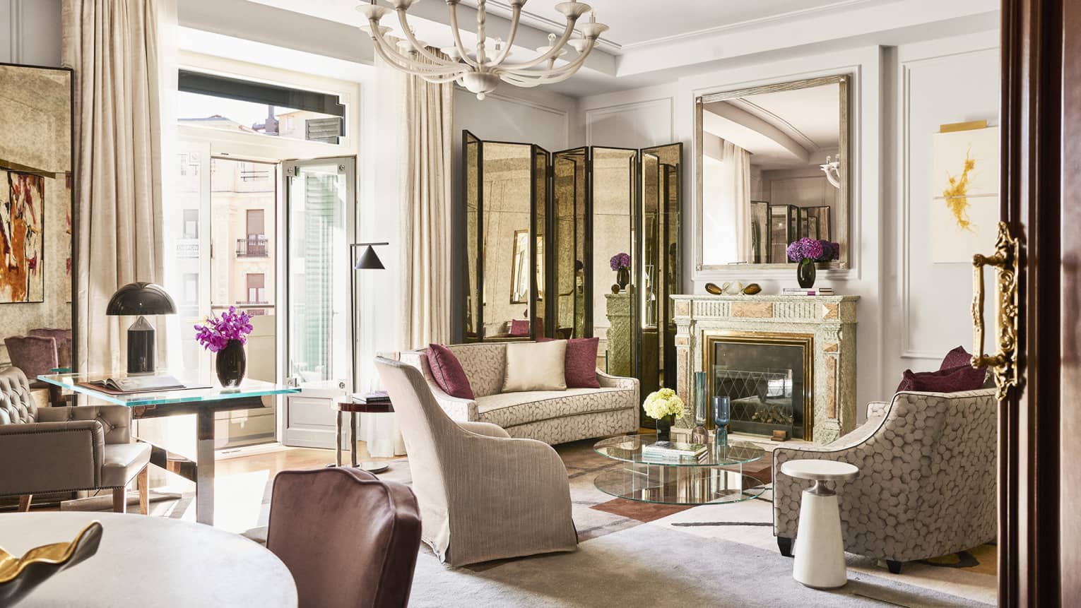 Ornate living room with chandelier, two two-person sofas, arm chair, glass doors to terrace