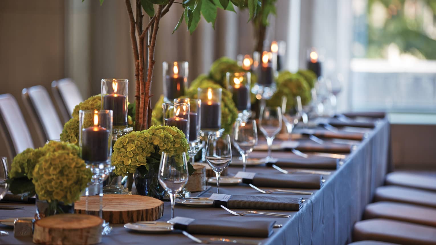 Black pillar candles in votives, green flowers, wine glasses along banquet table
